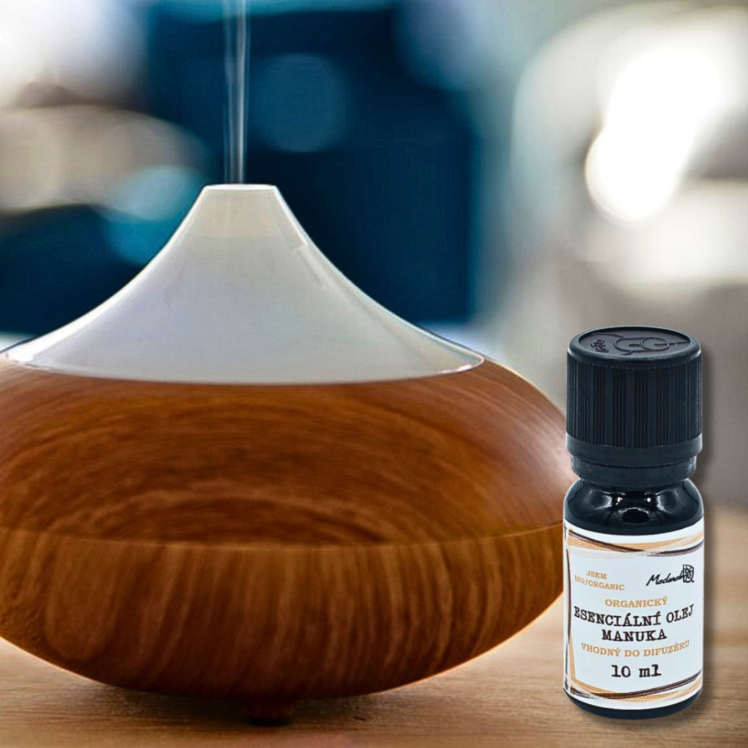 Wood-grain ultrasonic diffuser releasing mist beside a 10 ml bottle of Medarek Organic Manuka Essential Oil labeled “suitable for diffusers.